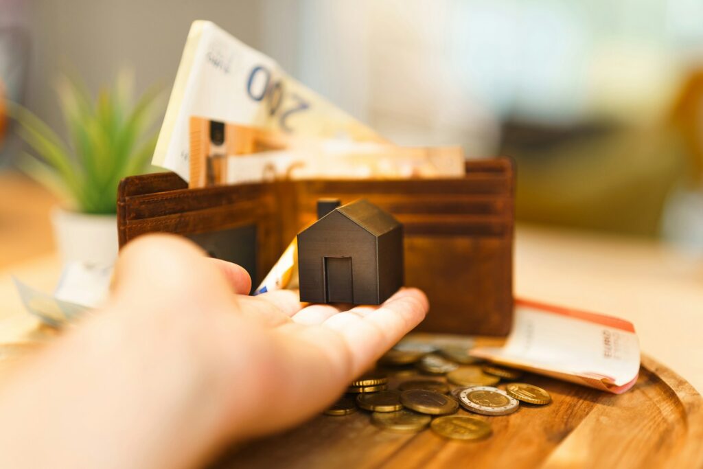 A person holding a small house and some money